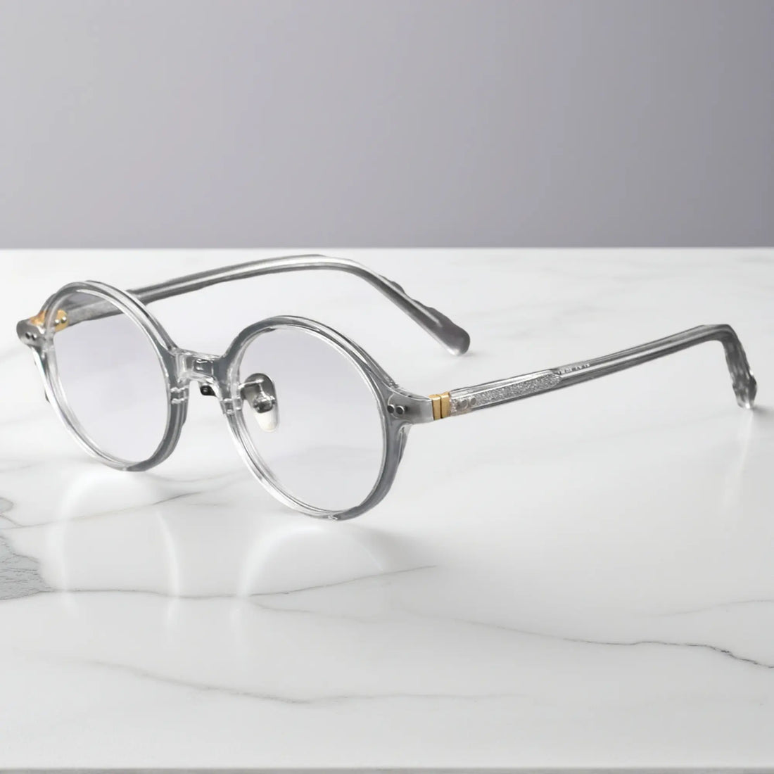 Clear round eyeglasses showing titanium nose pads and metal-insert hinges