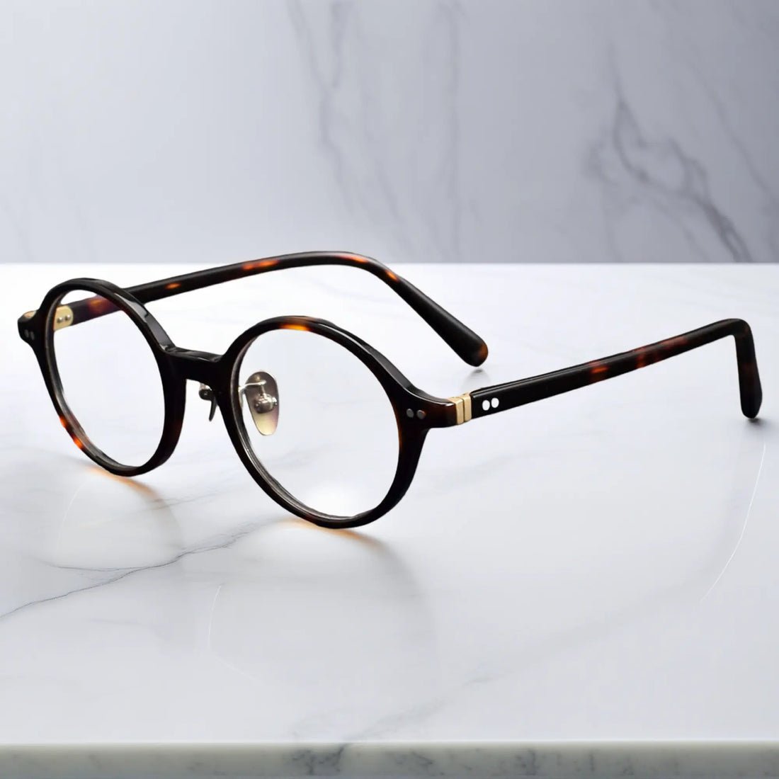 Tortoise round eyeglasses showing titanium nose pads and metal-insert hinges
