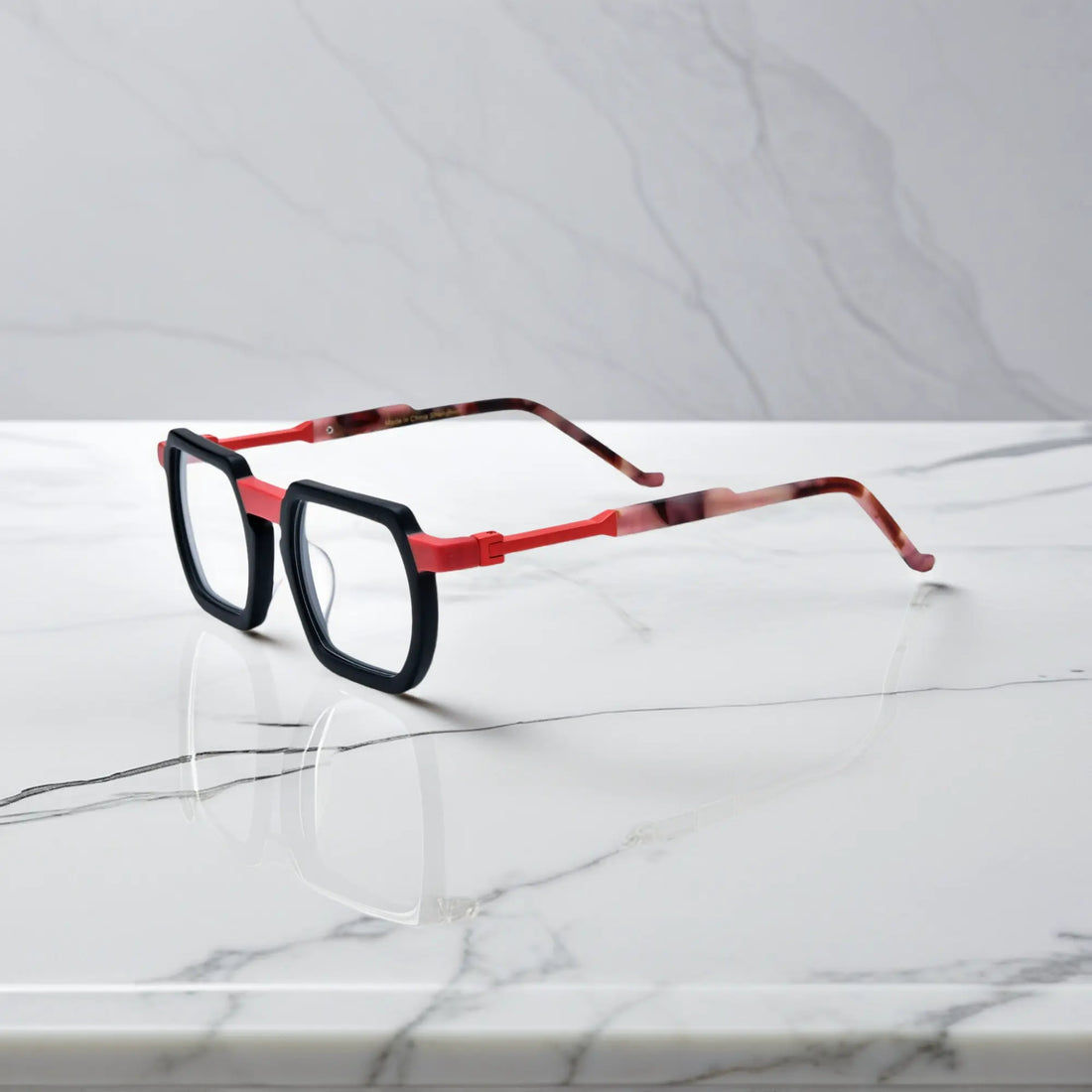 Side profile of dramatic matte black frames with wine red detailing and bold geometry