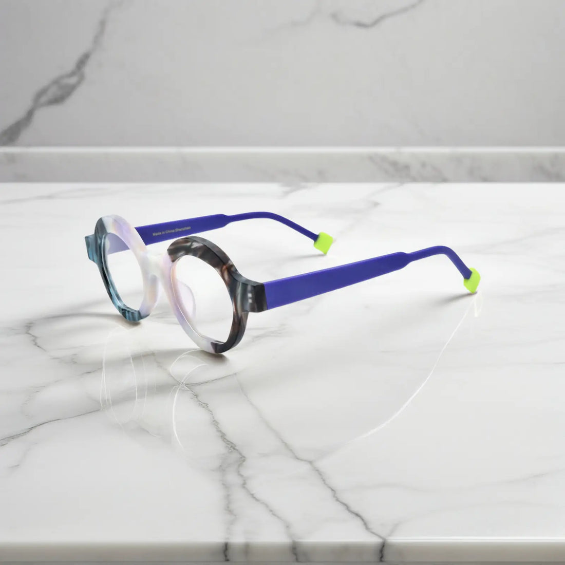 Side angle showing Ice Marble variant with geometric frame lines and smooth matte acetate material