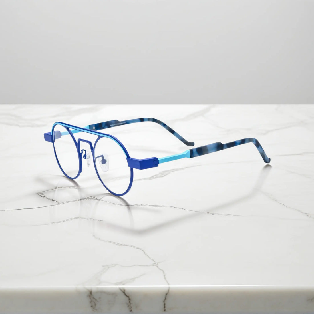 Side profile showing the slim titanium arms and hinge structure in Glacier Blue icy titanium aviator frame with a cool, futuristic tone
