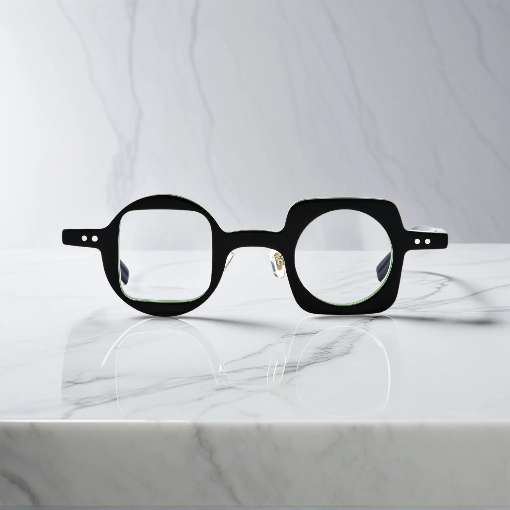 Front image of VoyueLens Designer Series asymmetrical eyeglasses featuring bold black-green acetate frame with artistic asymmetry.