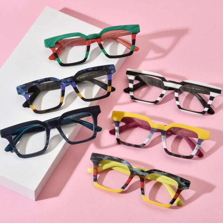 Group display of VoyueLens™ BlockForm Square Eyeglasses in six color variants including Jungle Stripe, Midnight Fade, Zebra Noir, Indigo Mist, Lemon Sorbet, and Citrus Fade – laid out on pink background in aesthetic top-down view.