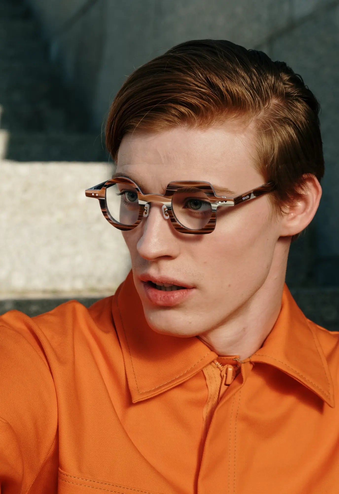 Lifestyle image of a model wearing VoyueLens brown stripe asymmetrical eyeglasses, showcasing artistic design and featherlight acetate comfort.