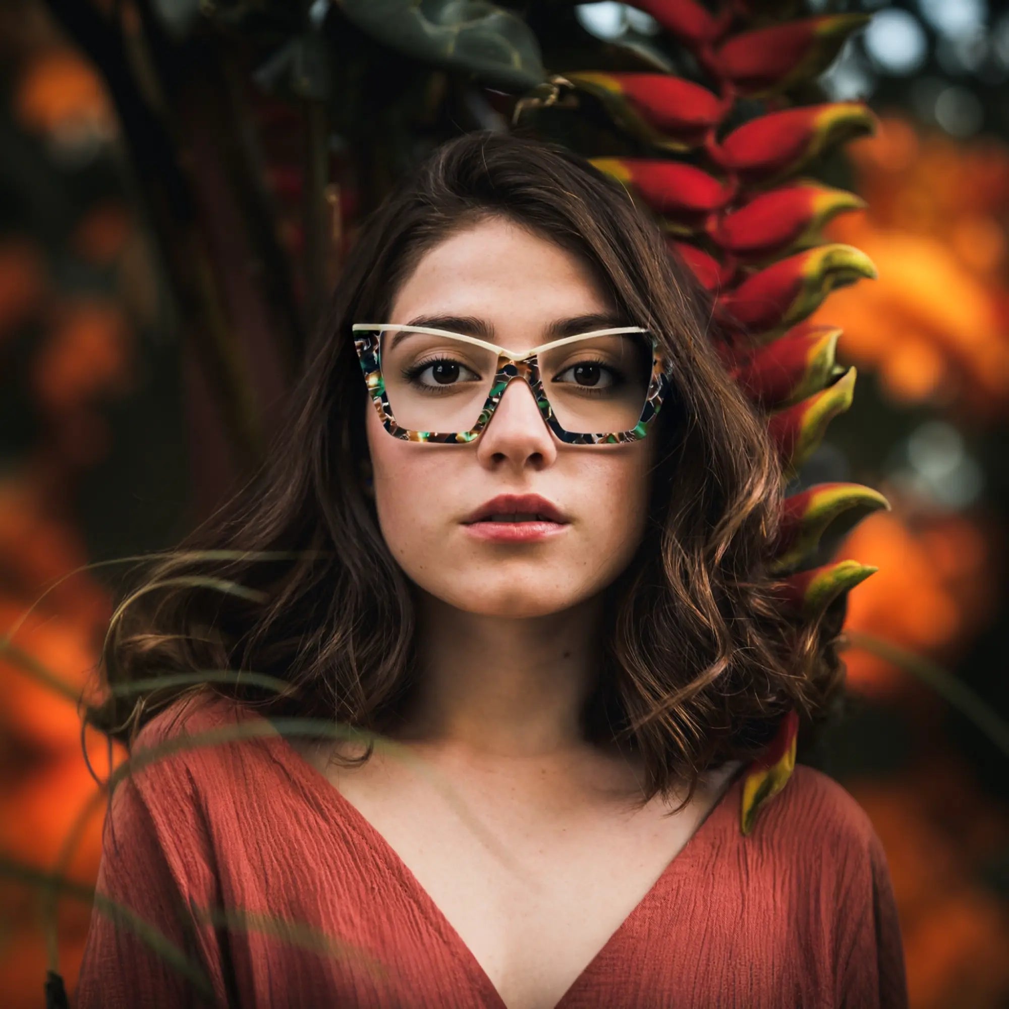 A young woman wearing Olive Tortoise VoyueLens™ oversized cat-eye glasses, styled in a natural setting to reflect earthy, vintage-inspired fashion