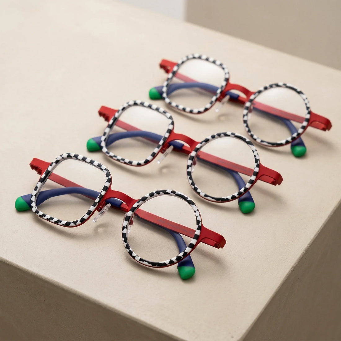 Multiple VoyueLens Checker Clash Red eyeglasses displayed together, emphasizing bold checker rims and asymmetrical design identity from BARLEDEAR.