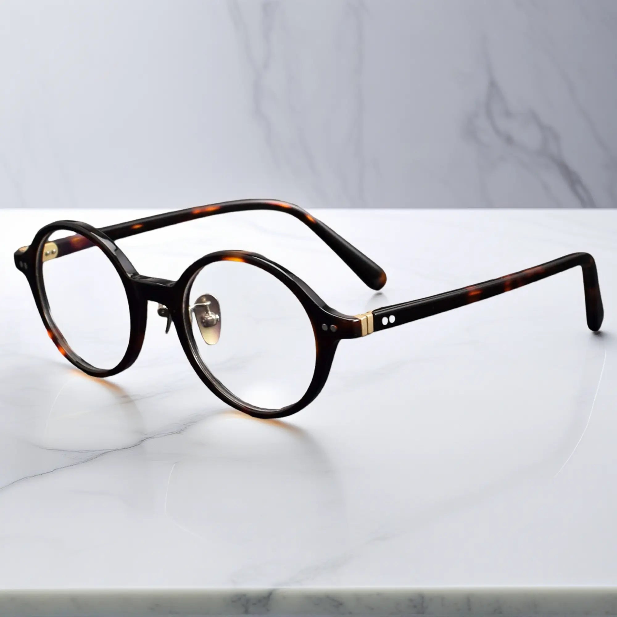 Tortoise round eyeglasses showing titanium nose pads and metal-insert hinges
