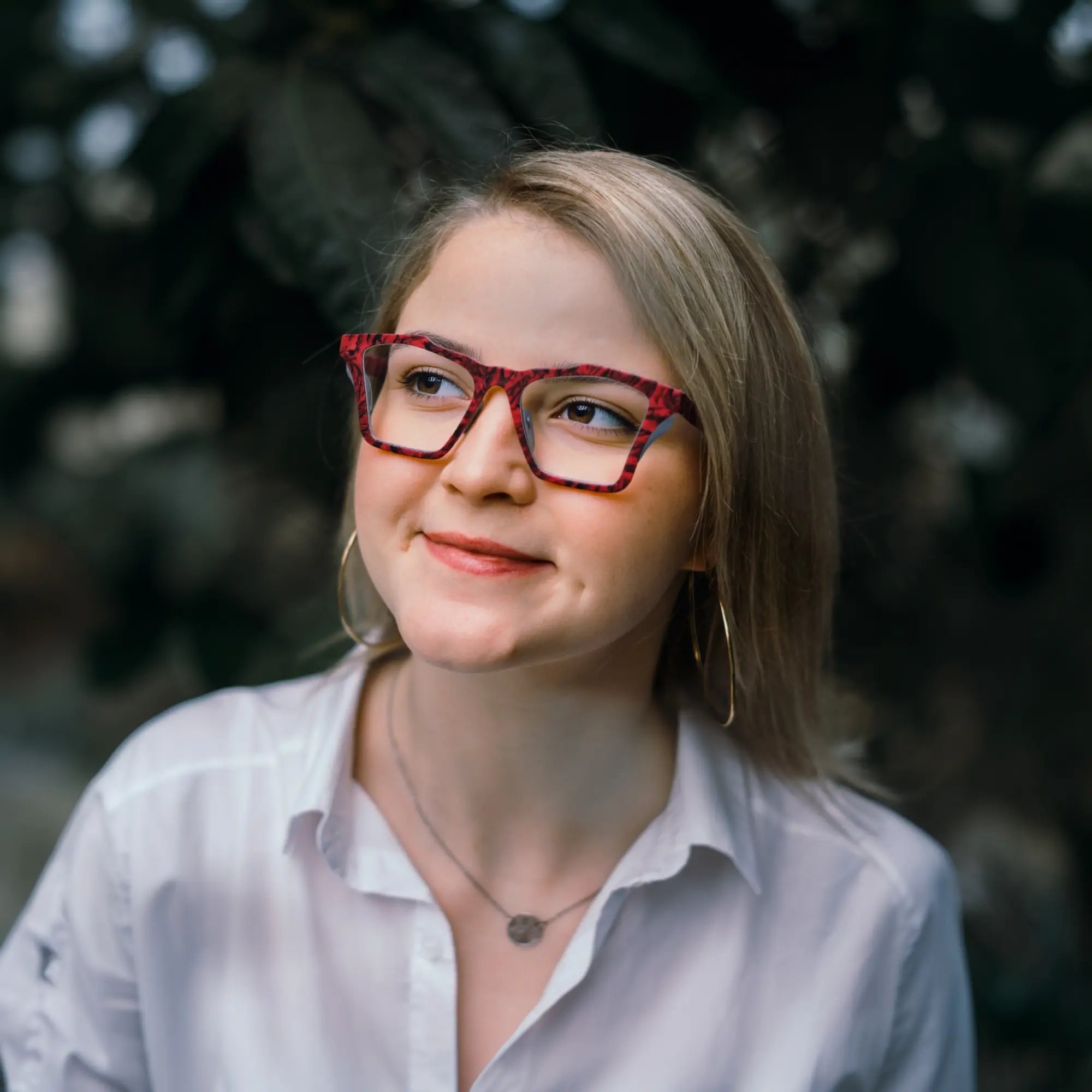 Model wearing VoyueLens™ Crimson Nebula butterfly frame in matte crimson red with cosmic black accents, demonstrating stylish fit for wide faces.