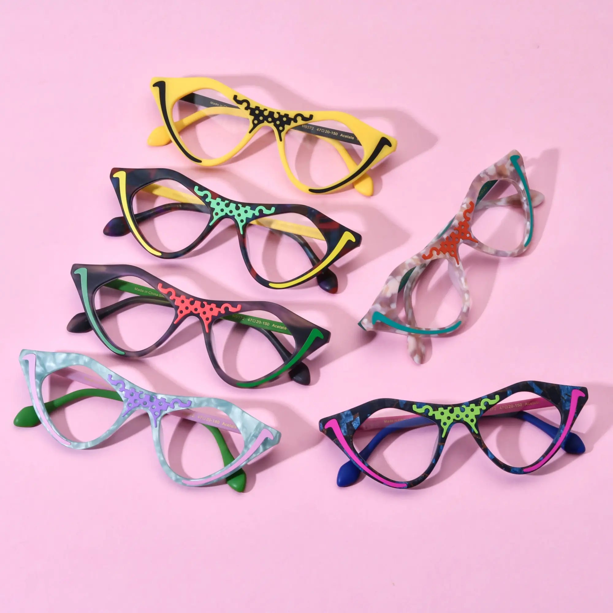 Group shot of six VoyueLens™ Retro Pixel Cat-Eye Glasses in assorted colors including Cyber Yellow, Color Burst, Jungle Moss, Mint Sorbet, Blush Marble, and Neon Pop displayed on a pastel pink background.
