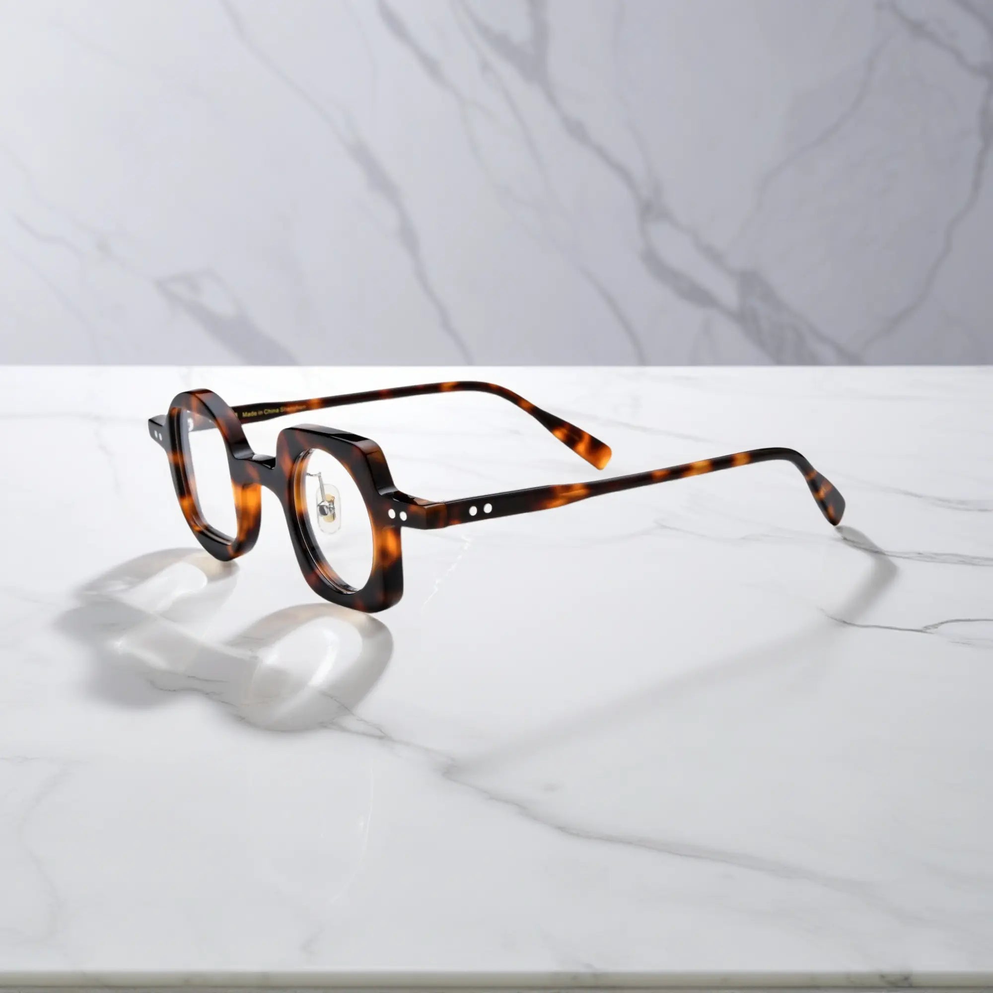 Side profile of VoyueLens tortoise asymmetrical glasses with polished acetate finish, silicone nose pads, and durable standard metal hinges.
