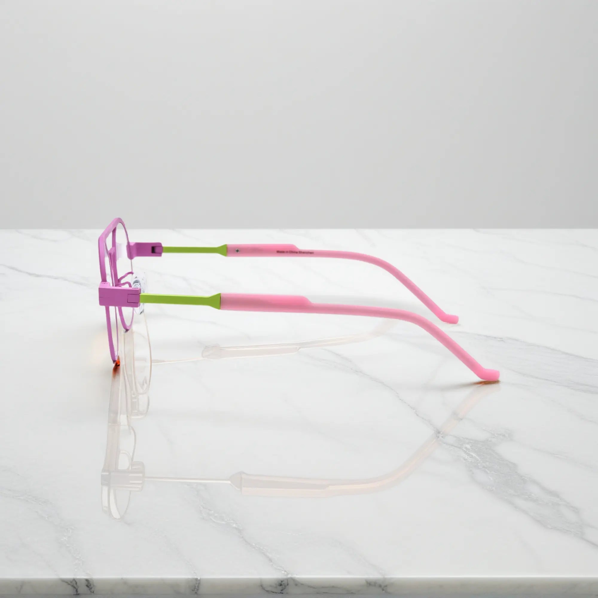 Side profile showing the slim titanium arms and hinge structure in Candy Lime color-block titanium frame with pink-green tones, part of the NeoPilot series.showing temples