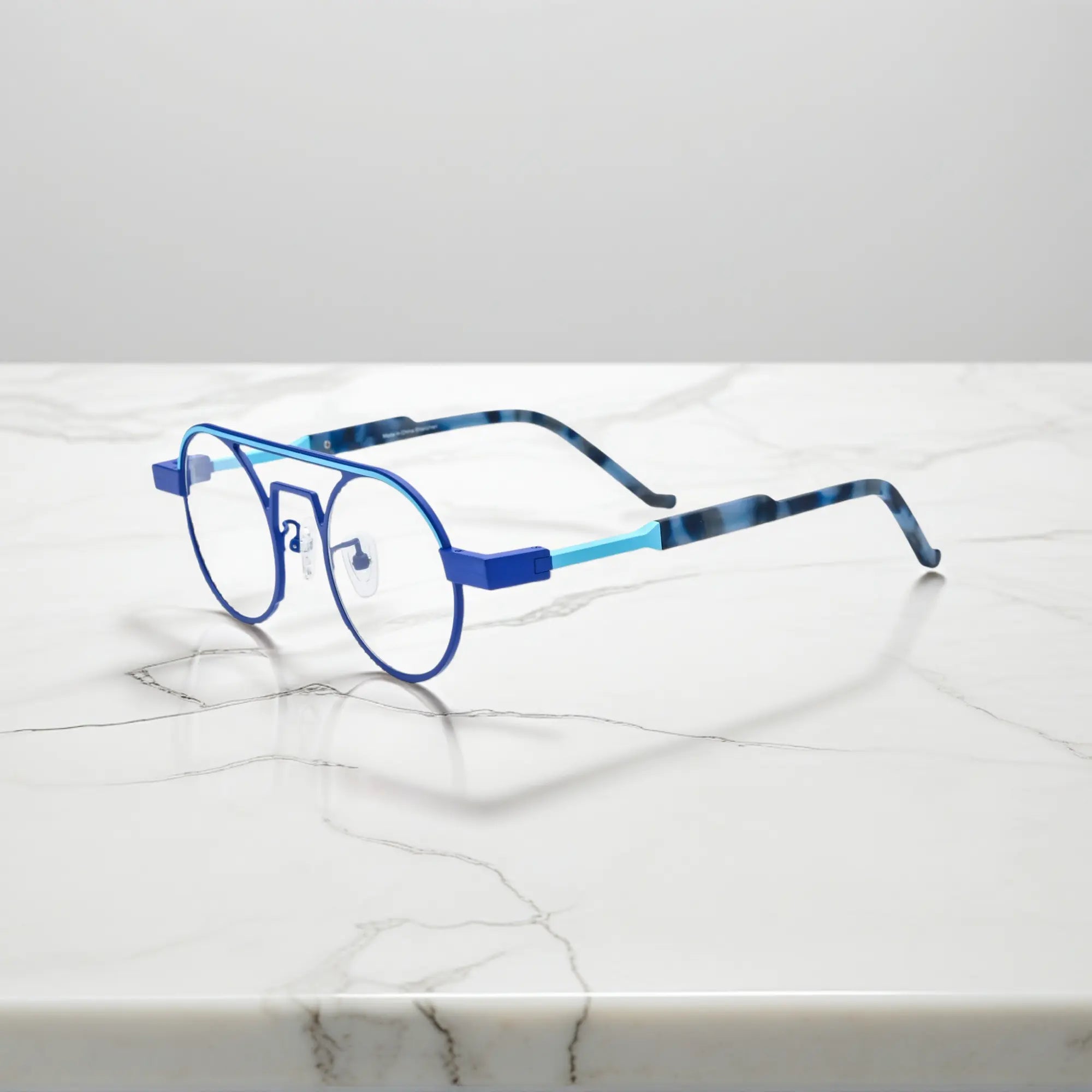 Side profile showing the slim titanium arms and hinge structure in Glacier Blue icy titanium aviator frame with a cool, futuristic tone