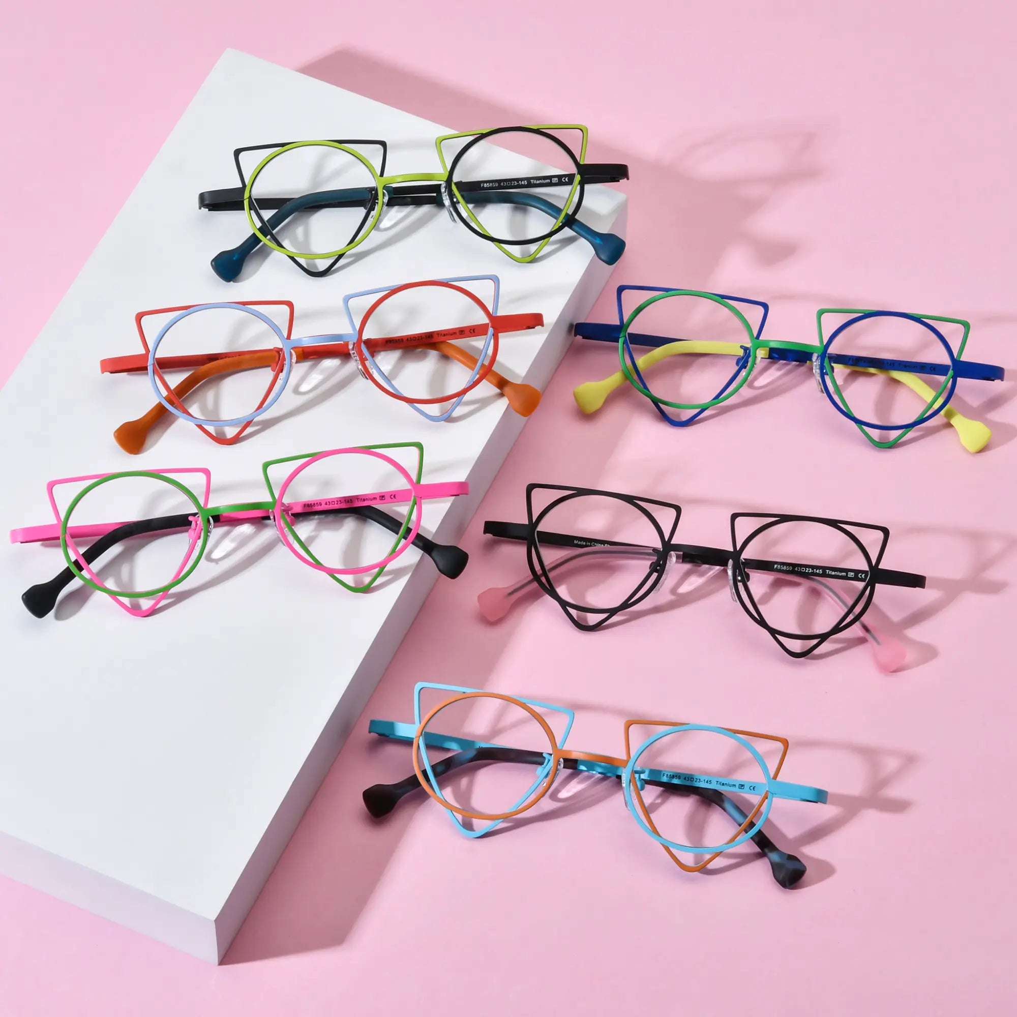 Overview image of VoyueLens™ VL185859 geometric titanium glasses in all six color variants including Lime Black, Tangerine Blue, Matte Black, Fuchsia Lime, Cobalt Chartreuse, and Skyfire Red on a pink background