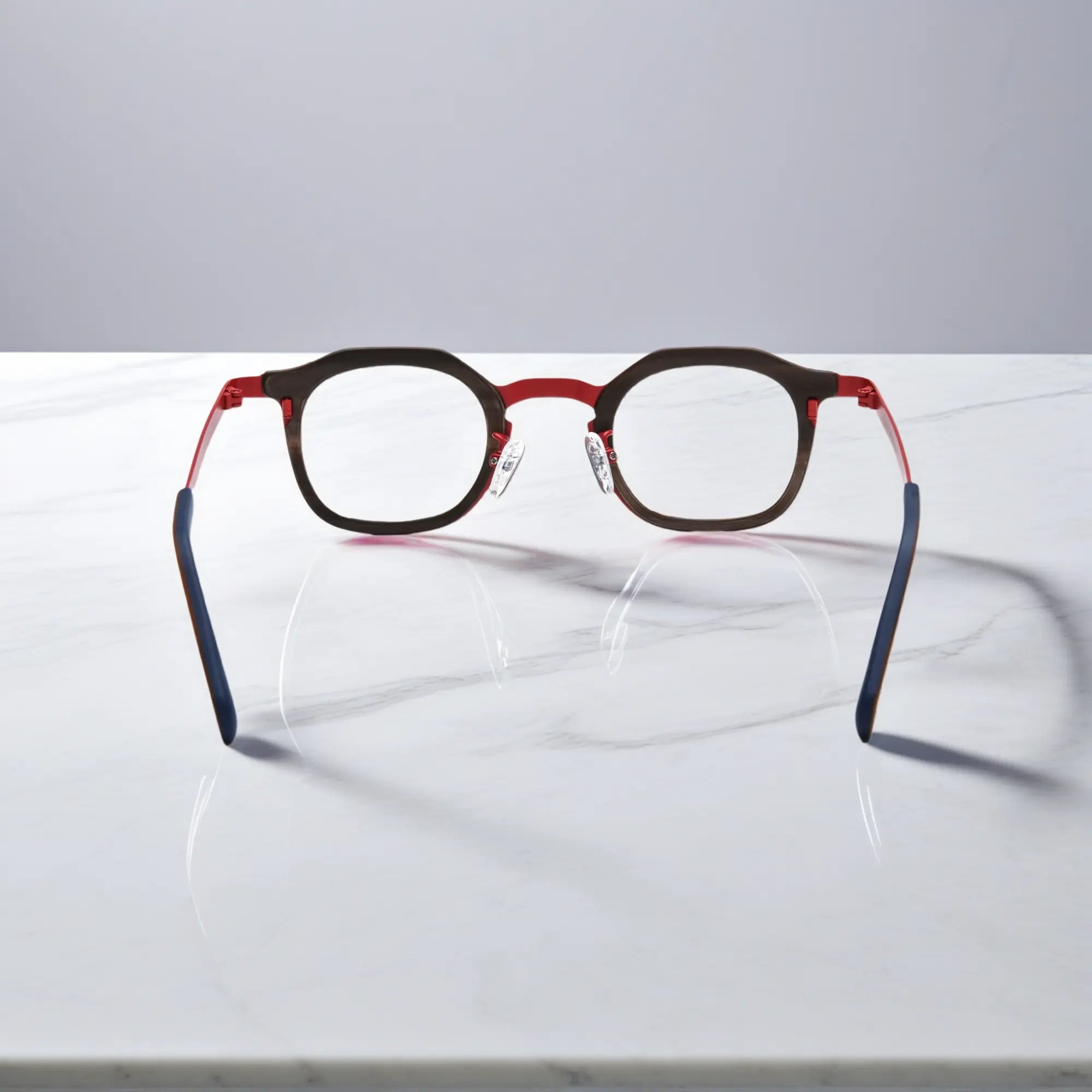 Rear view of VoyueLens™ Crimson Drift eyeglasses showing a warm red acetate front with amber pattern and clean titanium temples.