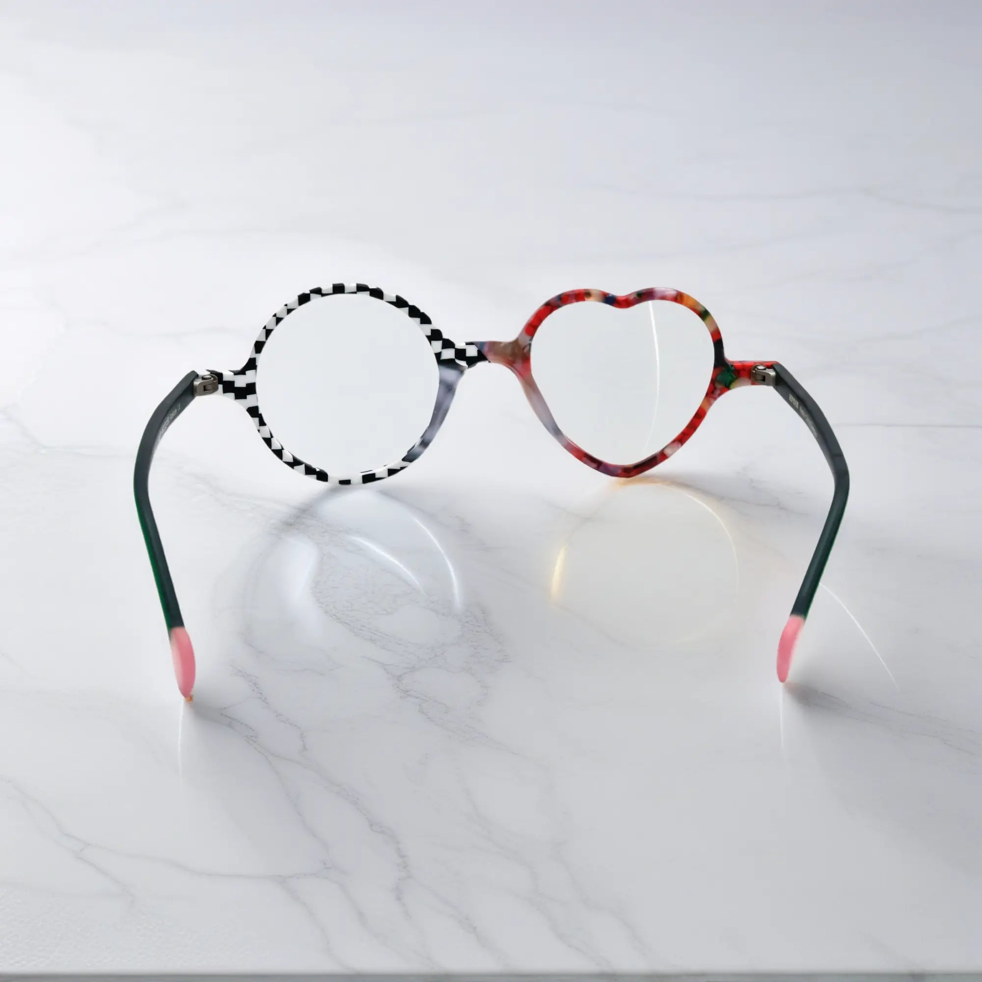 Back view of VoyueLens™ VL19377 in Checker Red Pop, showing full silhouette and lens contrast. Bold red and black asymmetrical frame with heart and round lenses.