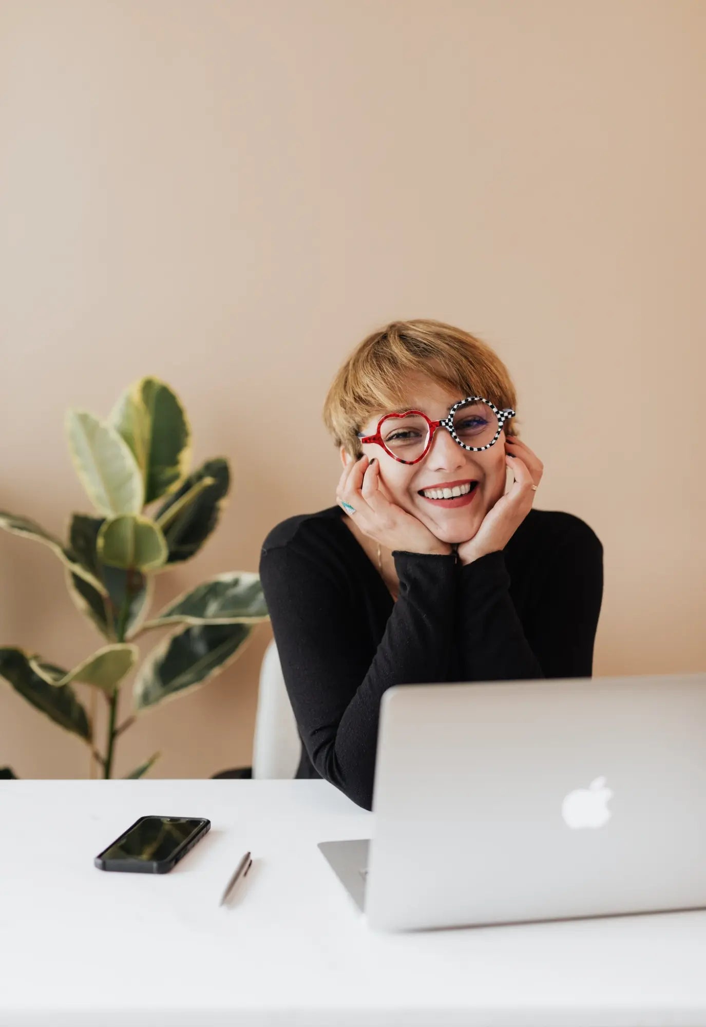 Model showcasing the Checker Red Pop VoyueLens™ Whimsy Pop frame in a lifestyle setting. Bold red and black asymmetrical frame with heart and round lenses.