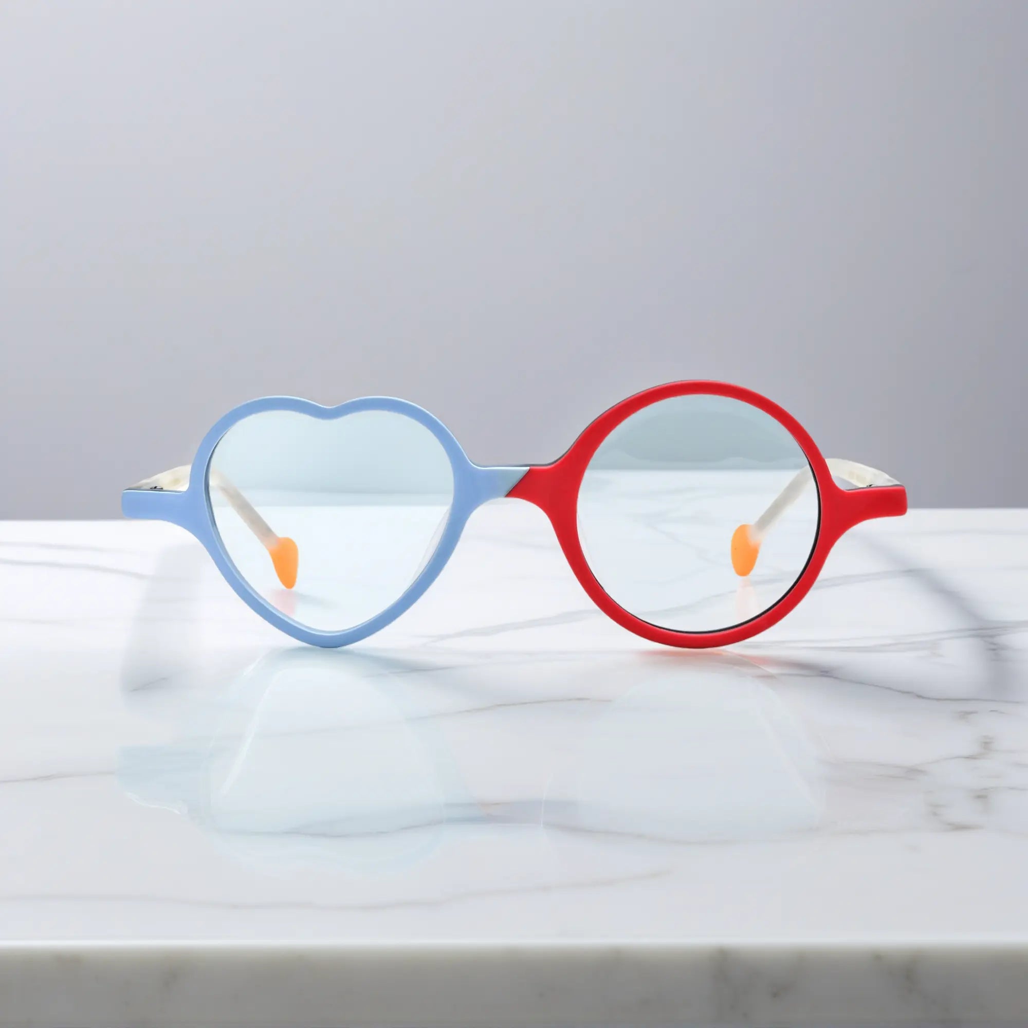 Front view of VoyueLens™ VL19377 in Ice Blue Cherry, highlighting heart and round lens design. Cool-toned ice blue paired with a cherry red accent in playful shape.
